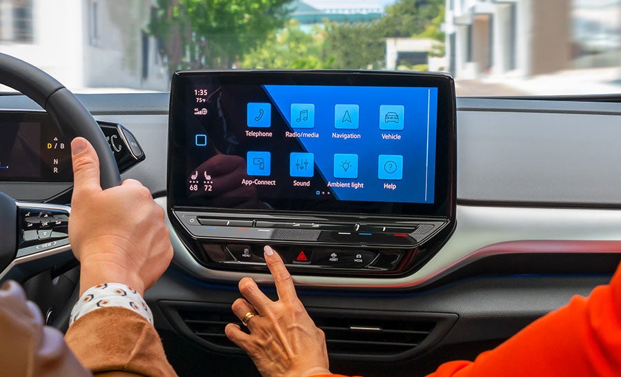 A close-up shot of a woman’s hand touching the ID.4 available 12" touchscreen display.