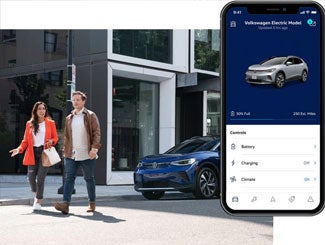 Street level shot of a man and woman walking away from a parked ID.4 in Dusk Blue Metallic. The myVW app is displayed on a superimposed mobile phone.