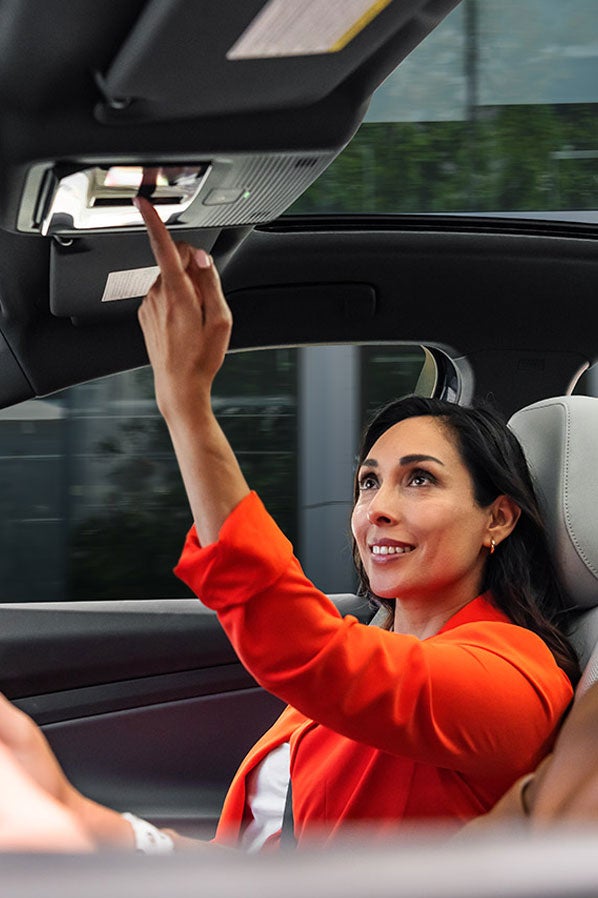A man and woman sit in the front seats of an ID.4 while the woman in the passenger seat adjusts the controls for the sunshade.