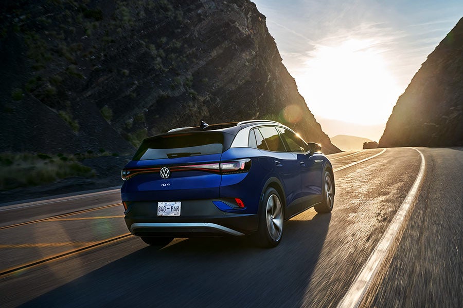 A rear view of an ID.4 in Dusk Blue Metallic, driving along a mountain road.