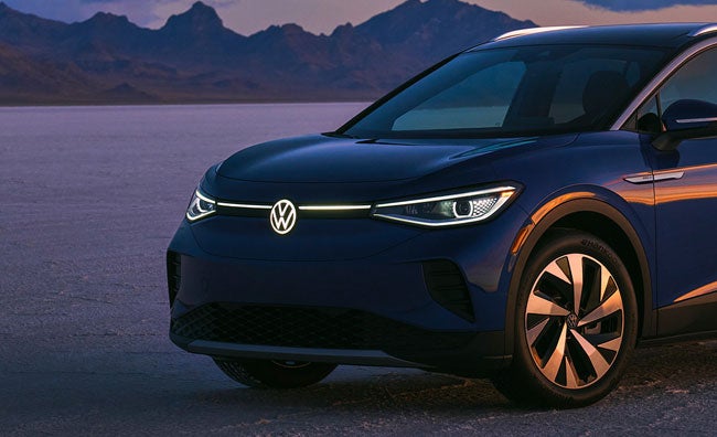 A ¾ front of an ID.4 in Dusk Blue Metallic in a natural sunset setting.