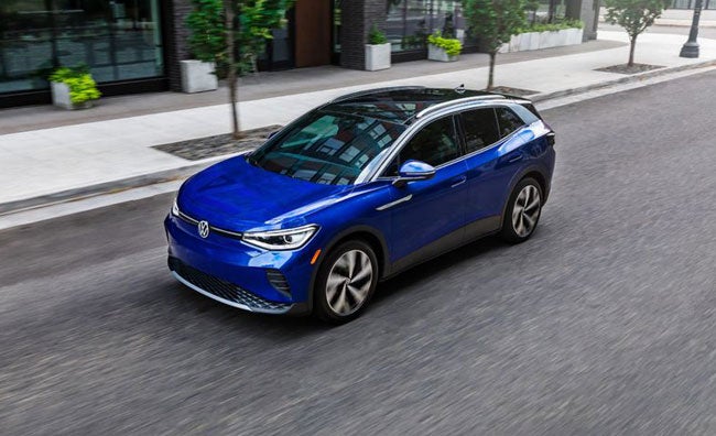 A driver’s side, angled profile shot of an ID.4 in Dusk Blue Metallic parked on an urban street.